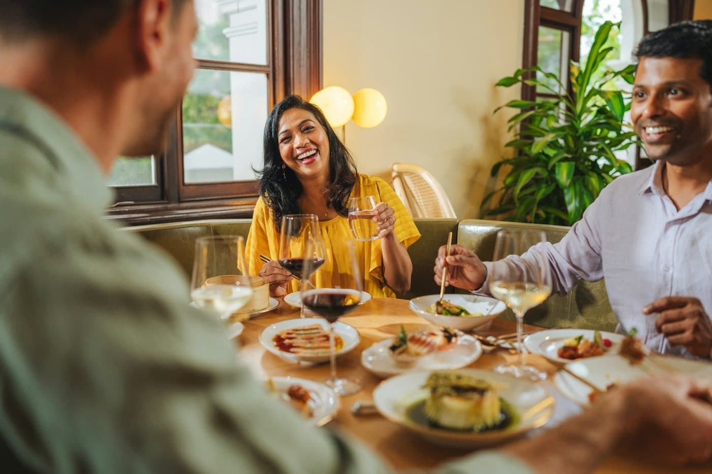 Four friends laughing over dinner at a restaurant table