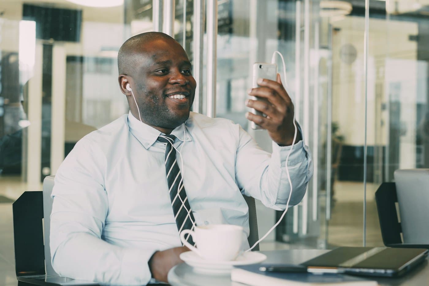 A businessman in a shirt and tie smiling at his phone in an office