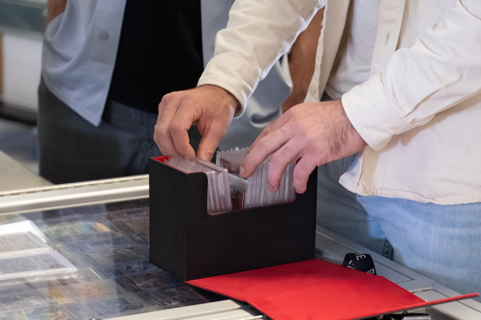 A collector flipping through graded trading cards in a display case
