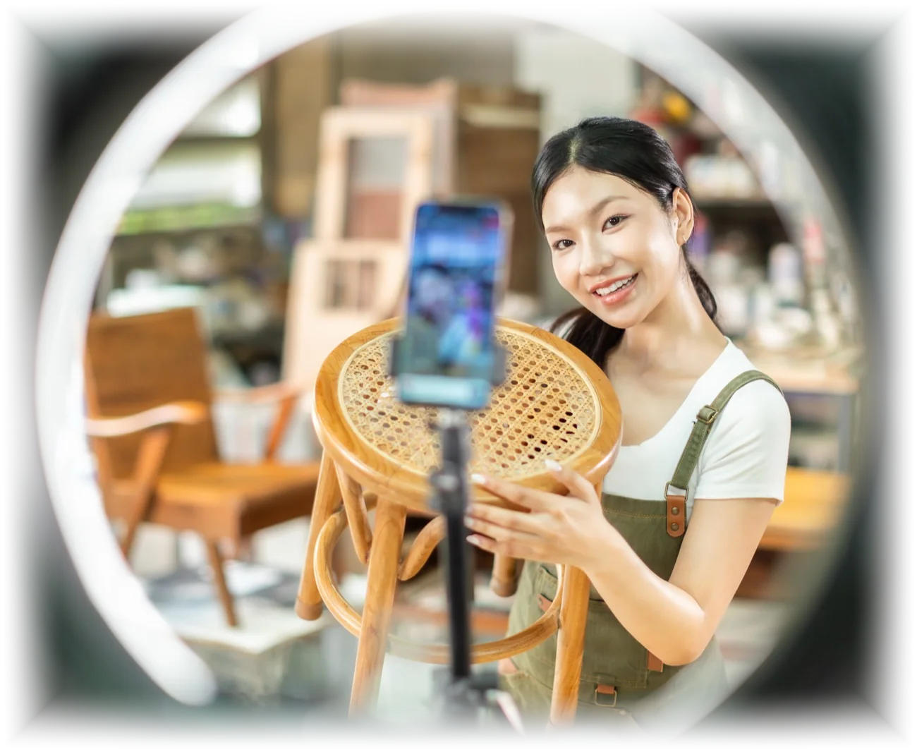A seller holding up a stool to her phone on a ring light while live streaming